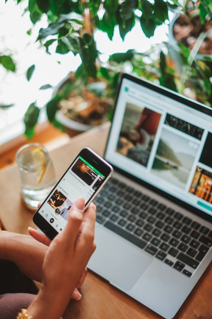 Home A cozy workspace featuring a smartphone and laptop used for social networking surrounded by greenery.