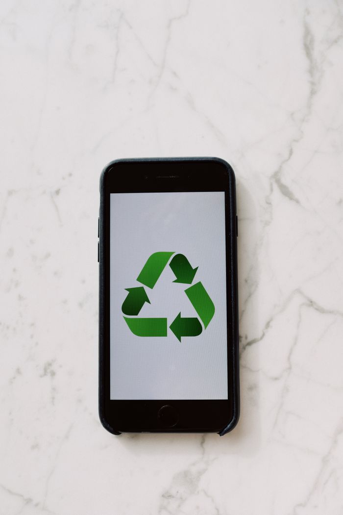 Offerings Mobile phone displaying a green recycling symbol, symbolizing sustainable technology.